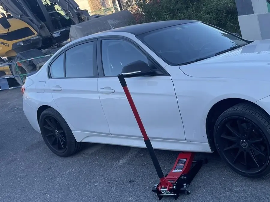 Montage de pneus sur une BMW blanche devant une habitation